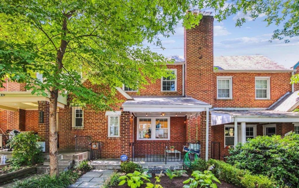 Two-story red brick single-family home with a covered front porch and garden