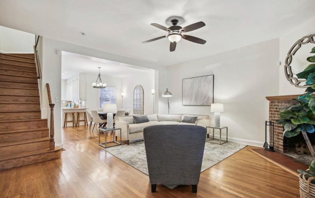 Open living room with hardwood floors flowing toward dining and kitchen